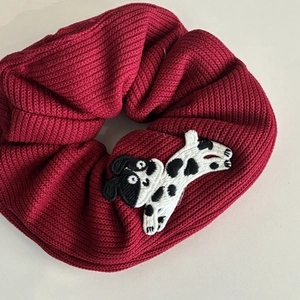Close-up of a burgundy knit scrunchie with a cute dalmatian puppy embroidery detail