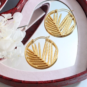 Elegant gold titanium steel hoop earrings with tropical leaf cutout in a heart-shaped box