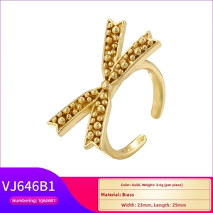 Close-up of gold brass bow ring featuring intricate beaded texture and vintage relief