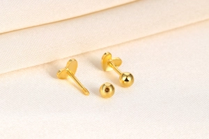 Detailed macro view of S925 silver heart screw-back studs with gold finish and polished surface