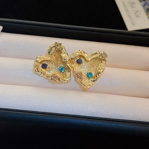 Macro detail of gold-plated heart earrings with colorful rhinestones on jewelry box