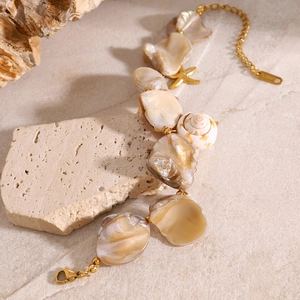 Golden starfish and shell charm bracelet on beach rock, nautical summer jewelry detail