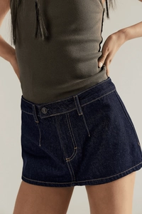 Dettaglio del design della vita della minigonna in denim blu scuro con top a coste oliva