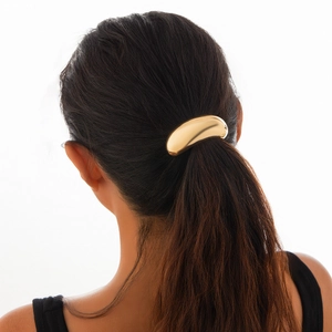 Close-up of golden geometric metal hair ring showing polished surface on a ponytail