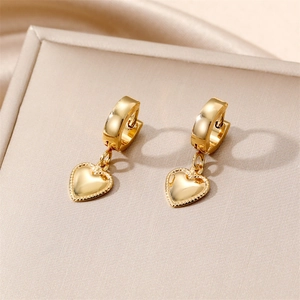 Hip hop style gold heart hoop earrings with intricate beaded edges on a beige display