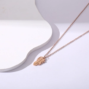 Elegant rose gold stainless steel necklace featuring a minimalist leaf pendant on a white surface