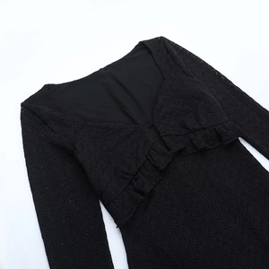 Détail d'une robe noire à manches longues avec texture dentelle et volants sur col en V