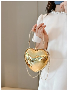 Detailed view of glossy gold heart-shaped acrylic bag with elegant metal chain strap