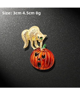 Detail of Halloween cat and pumpkin brooch with green gem eyes and orange enamel