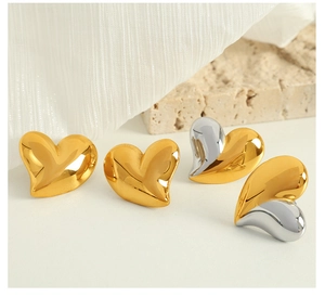 Détails de boucles d'oreilles cœur polies miroir en or et argent sur fond texturé