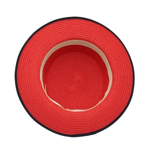 Close-up of red straw hat featuring spiral weave texture and black contrast edging