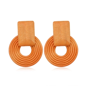 Macro detail of geometric hollow wood earrings in brown with concentric circular patterns