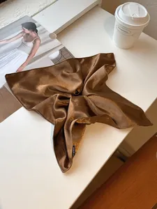 Detailed view of coffee-colored satin scrunchie with a black Hand Made label on fabric