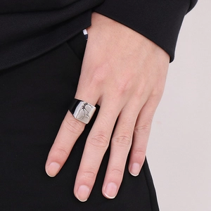 Detailed view of wide stainless steel ring with black cracked texture on a model's hand