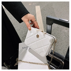Close-up of white quilted PVC jelly bag with gold chain and flower hardware on books