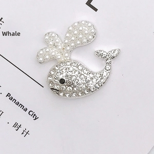 Détail macro d'un charme baleine en alliage de zinc avec strass brillants et perles blanches