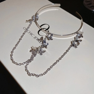 Detailed close-up of silver butterfly pendants and long tassel chains on a metal arm cuff