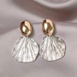 Detail of gold and silver plated fan-shaped earrings with brushed metal texture and tassels