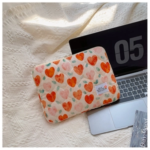 Quilted laptop sleeve with heart patterns and zipper shown on a soft knit blanket