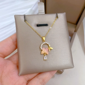 Detail of pink butterfly pendant with pearls and cubic zirconia on a gold chain