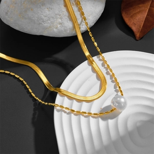Gold layered stainless steel necklace with snake chain and white pearl pendant on stone