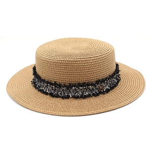 Detailed texture of natural boater hat with tweed trim and golden 'M' metal plaque