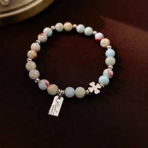 Detailed macro shot of blue beaded necklace with silver clover and handmade metal charms