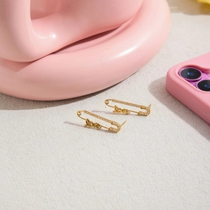 Détail de boucles d'oreilles épingle à nourrice dorées avec lettres LOVE et cristaux