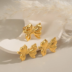 Elegant gold bow jewelry set featuring a polished ring and stud earrings on a white pedestal