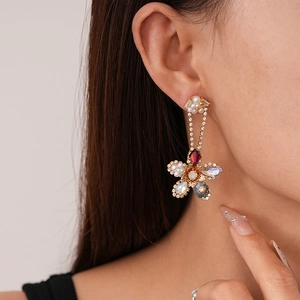 Macro detail of floral drop earrings with rhinestones, pearls and colorful gemstones