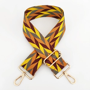 Close-up of geometric herringbone woven bag strap with gold metal spring buckles
