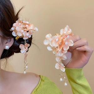 Detailed view of elegant fabric flower hair clip with pearl tassels on model's hair.