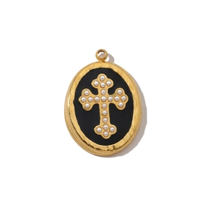 Macro shot of oval gold pendant featuring a black inlay and white pearl cross detail