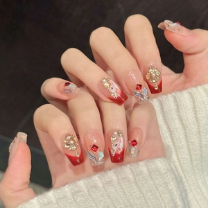 Detail of red gradient press-on nails with 3D crystal, pearl, and white floral art