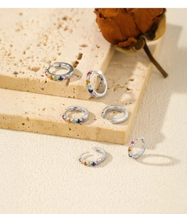 Set of six colorful rainbow S925 sterling silver hoop earrings on a stone surface