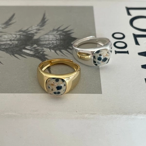 Detail view of 925 silver and 18K gold zebra stone rings on an artistic sketch background