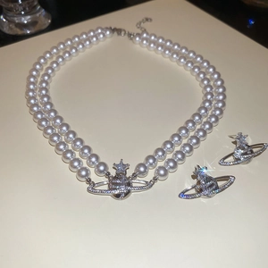 Detailed close-up of double-layer pearl necklace with rhinestone Saturn orb pendant and earrings