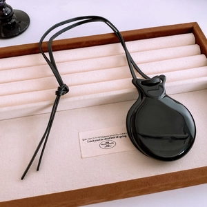 Detail of minimalist black leather cord necklace with a glossy resin irregular pendant