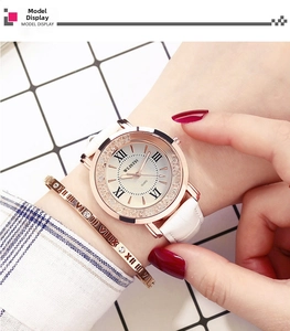 Close-up of elegant women's watch with white leather strap and crystal rose gold bezel