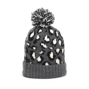 Detailed view of leopard print knit beanie with fluffy faux fur pom pom and ribbed cuff