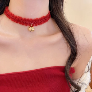 Détail du ras-du-cou en tricot rouge avec pendentif clochette dorée