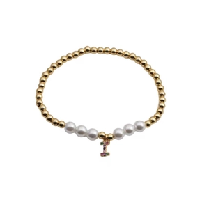 Detail view of pearl and gold bead bracelet featuring a colorful zircon letter I charm