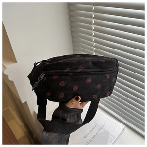 Detail of black corduroy fanny pack with red strawberry patterns and adjustable strap