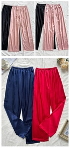 Flat lay of silk satin wide-leg lounge pants in four colors with home decor accents