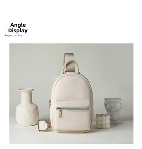 Close-up of cream white textured faux leather chest bag with metal zipper and strap