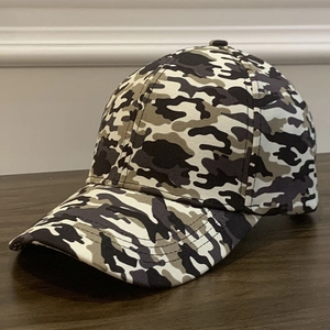 Detailed texture of cotton camouflage baseball cap on dark wood grain surface