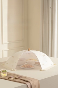 Vue détaillée d'une cloche alimentaire en maille beige protégeant les plats sur table