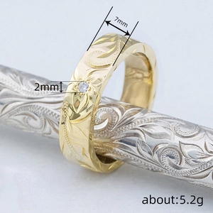 Engraved floral gold ring with a 2mm white diamond on an ornate silver stand