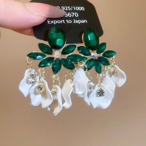 Detail of vintage leaf earrings with green crystals and white petal charms