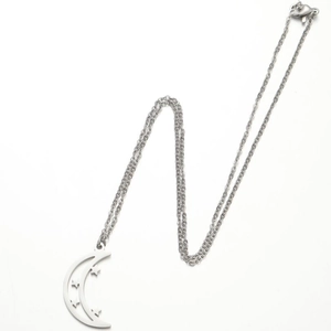 Detailed view of silver crescent moon pendant with hollow star engravings on a fine chain
